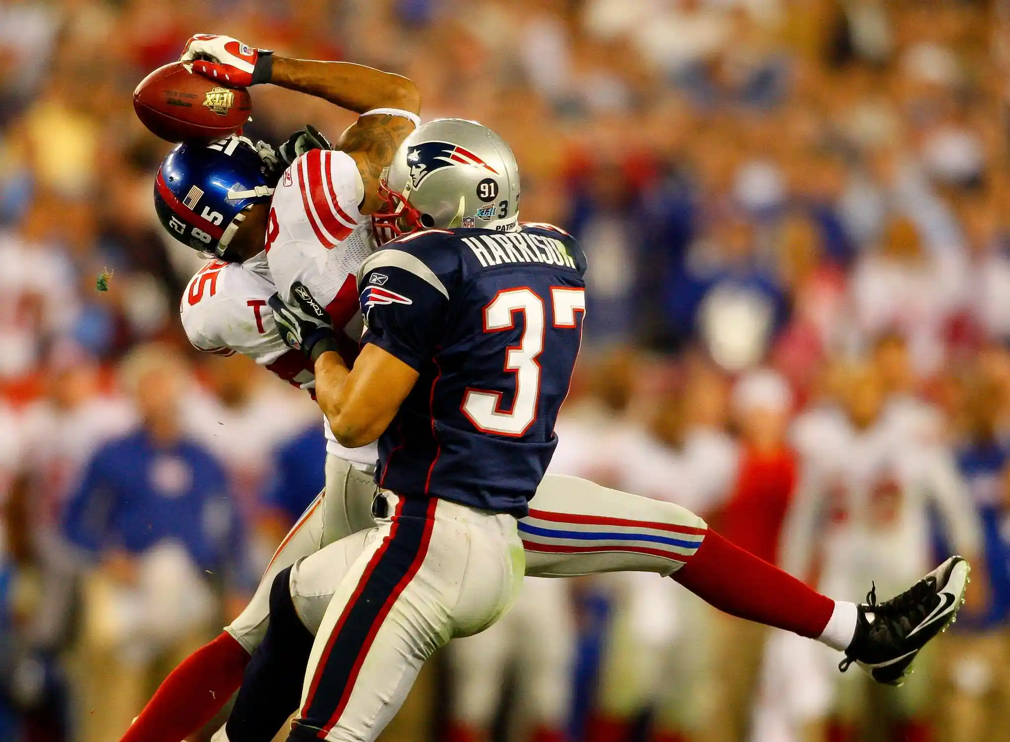 Giants receiver David Tyree catches a pass while in the clutches of Patriots safety Rodney Harrison en route to New York's 17-14 victory over New England in Super Bowl XLII.